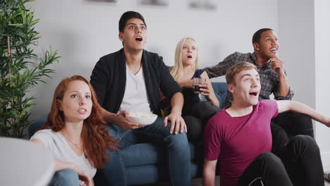 Group-Of-College-Friends-Celebrating-Whilst-Watching-Sports-Game-On-TV-In-Shared-House