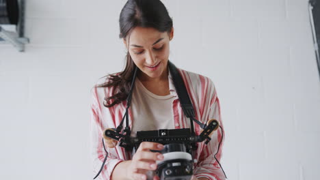Female-Crew-Member-On-Video-Film-Set-Operating-Wireless-Follow-Focus-Module-In-White-Studio