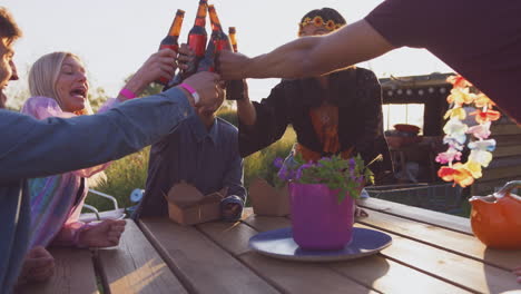 Group-Of-Young-Friends-At-Music-Festival-Sitting-Around-Table-And-Drinking-Beer