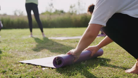 Reife-Freundinnen-Rollen-Am-Ende-Der-Outdoor-Yoga-Stunde-Trainingsmatten-Auf-Gras-Zusammen