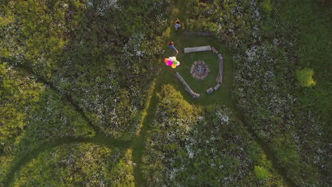 Drone-Shot-Of-Two-Female-Friends-Camping-At-Music-Festival-Running-Through-Field-With-Balloons
