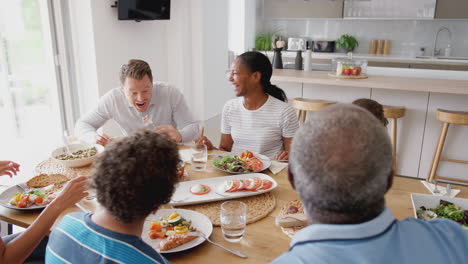 Multi-Generation-Mixed-Race-Family-Eating-Meal-Around-Table-At-Home-Together