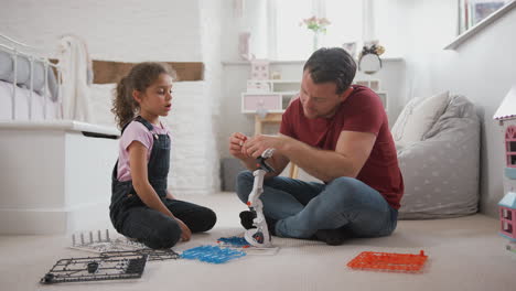 Father-And-Daughter-In-Bedroom-Building-Robot-Kit-Together