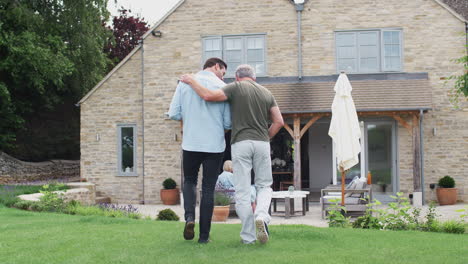 Rear-View-Of-Senior-Father-With-Adult-Son-Walking-In-Garden-Together