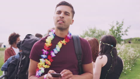 Man-With-Friends-At-Music-Festival-Using-Mobile-Phone-To-Arrange-Meeting