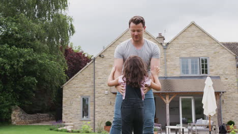Father-Playing-Game-With-Daughter-In-Garden-At-Home-Spinning-Her-Around-In-The-Air