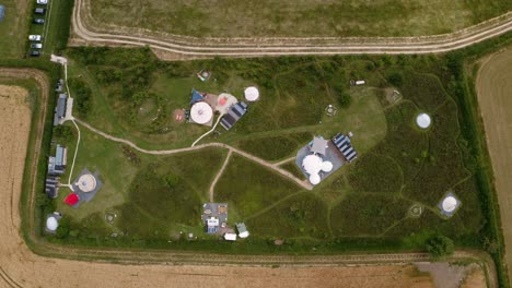 Drone-Shot-Of-Luxury-Campsite-With-Yurts-And-Teepees-In-Countryside