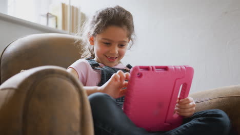 Mädchen-Sitzt-Zu-Hause-Im-Sessel-Und-Spielt-Mit-Digitalem-Tablet