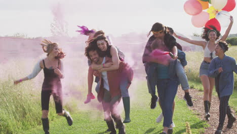 Group-Of-Excited-Young-Friends-Walking-Through-Music-Festival-Site-Carrying-Flares-And-Balloons
