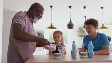 Grandfather-Serving-Ice-Cream-To-Grandchildren-In-Kitchen