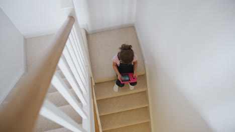 Mädchen-Sitzt-Zu-Hause-Auf-Der-Treppe-Und-Spielt-Mit-Einem-Digitalen-Tablet