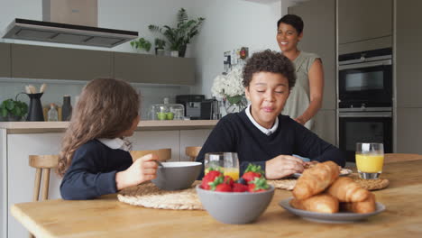 Madre-En-La-Cocina-Ayudando-A-Los-Niños-Con-El-Desayuno-Antes-De-Ir-A-La-Escuela.