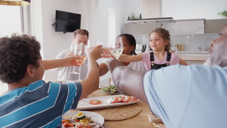 Mehrgenerationenfamilie-Mit-Gemischter-Rasse-Stößt-Vor-Dem-Gemeinsamen-Essen-Am-Tisch-Zu-Hause-An