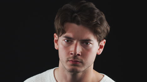 Head-And-Shoulders-Studio-Shot-Of-Unhappy-Man-Looking-At-Camera-With-Sad-Expression-In-Slow-Motion