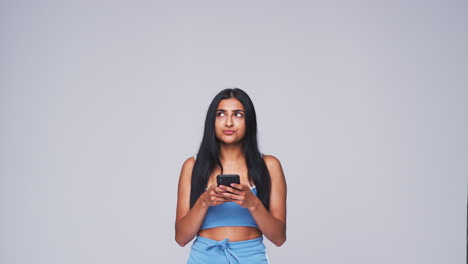 Studio-Shot-Of-Woman-Against-White-Background-Sending-Text-Message-On-Mobile-Phone-In-Slow-Motion