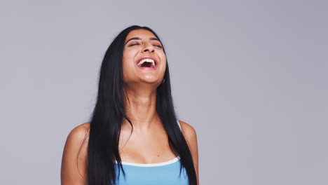 Head-And-Shoulders-Studio-Shot-Of-Woman-Laughing-At-Camera-In-Slow-Motion