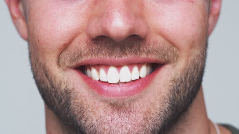Close-Up-Of-Mouth-As-Man-With-Perfect-Teeth-Smiles-At-Camera-In-Studio