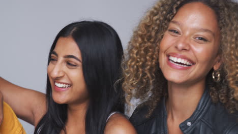 Group-Studio-Portrait-Of-Multi-Cultural-Female-Friends-Smiling-Into-Camera-Together-In-Slow-Motion