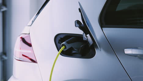Close-Up-Of-Hand-Removing-Power-Cable-From-Environmentally-Friendly-Zero-Emission-Electric-Car