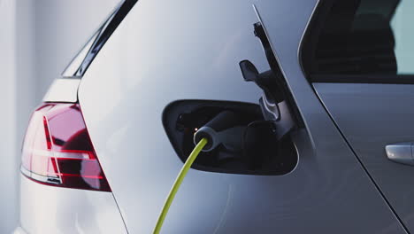 Close-Up-Of-Hand-Attaching-Power-Cable-To-Environmentally-Friendly-Zero-Emission-Electric-Car