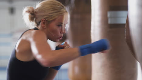 Female-Boxer-In-Gym-Training-With-Old-Fashioned-Leather-Punch-Bag
