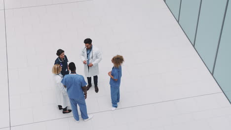 Overhead-View-Of-Medical-Staff-Having-Informal-Meeting-In-Lobby-Of-Modern-Hospital-Building