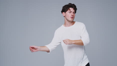 Wide-Angle-Studio-Shot-Of-Young-Man-Against-White-Background-Dancing-In-Slow-Motion