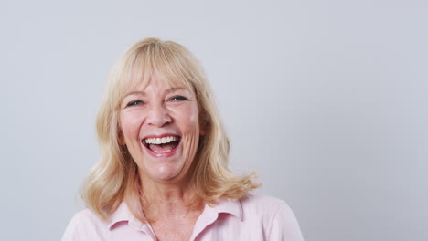 Studio-Shot-Of-Mature-Woman-Against-White-Background-Laughing-At-Camera