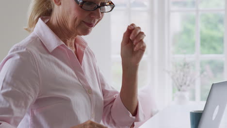 Mature-Woman-At-Home-Looking-Up-Information-About-Medication-Online-Using-Laptop