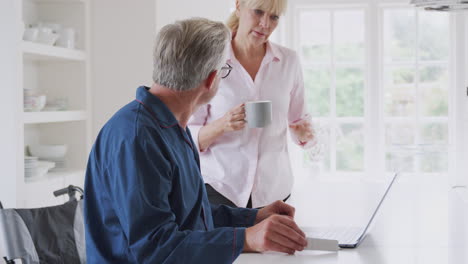 Älteres-Paar-Mit-Mann-Im-Rollstuhl,-Der-Online-Mit-Einem-Laptop-Nach-Informationen-über-Medikamente-Sucht