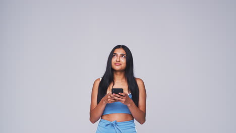 Studio-Shot-Of-Woman-Against-White-Background-Sending-Text-Message-On-Mobile-Phone-In-Slow-Motion