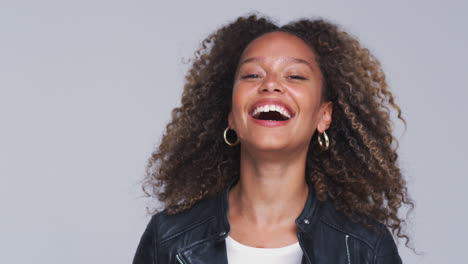 Head-And-Shoulders-Studio-Shot-Of-Woman-Wearing-Leather-Jacket-Laughing-At-Camera-In-Slow-Motion