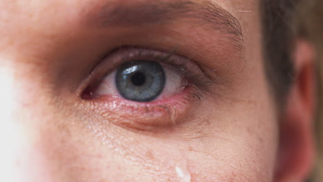Extreme-Close-Up-Of-Eye-As-Unhappy-Man-Cries-Into-Camera-In-Studio