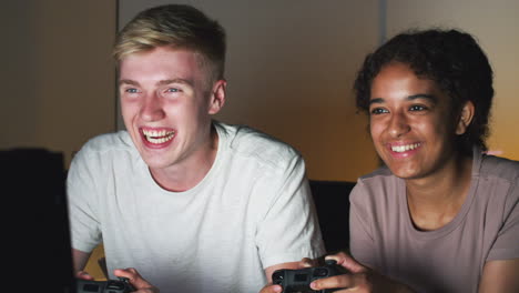 Teenage-Girl-Beating-Boy-As-They-Sit-On-Sofa-At-Home-Playing-Computer-Game