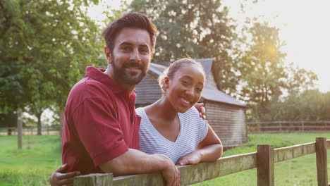 Portrait-Of-Romantic-Couple-Taking-A-Break-And-Resting-On-Fence-During-Walk-In-Countryside