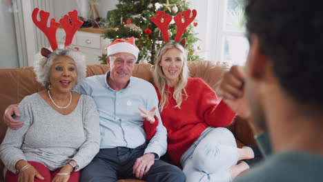 Erwachsene-Familie-Sitzt-Auf-Dem-Sofa-Und-Spielt-Zu-Weihnachten-Gemeinsam-Scharaden