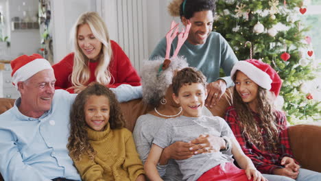 Porträt-Einer-Familie-Mit-Mehreren-Generationen,-Die-Auf-Dem-Sofa-Sitzt-Und-Gemeinsam-Weihnachten-Feiert