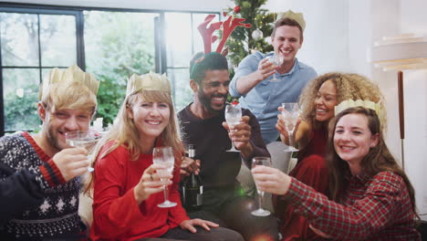 Portrait-Of-Friends-Celebrating-With-Champagne-After-Christmas-Dinner-Making-A-Toast-To-Camera