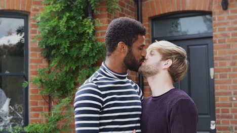 Portrait-Of-Gay-Male-Couple-Standing-Outside-New-Home-On-Moving-Day-Together-Kissing