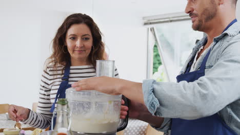 Man-And-Woman-Taking-Part-In-Kitchen-Cookery-Class-Tasting-Food