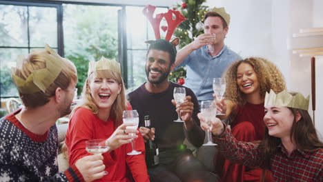 Portrait-Of-Friends-Celebrating-With-Champagne-After-Christmas-Dinner-Making-A-Toast-To-Camera
