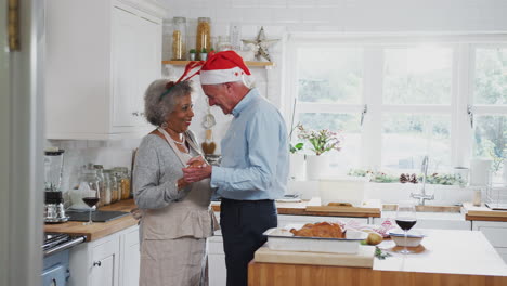Liebevolles-älteres-Paar-Mit-Kostümgeweihen-Tanzt-In-Der-Küche,-Während-Es-Das-Weihnachtsessen-Zubereitet