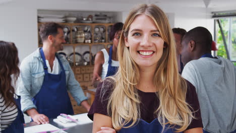 Portrait-Of-Smiling-Woman-Wearing-Apron-Taking-Part-In-Cookery-Class-In-Kitchen