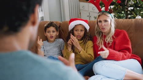 Familie-Sitzt-Auf-Dem-Sofa-Und-Spielt-Zu-Weihnachten-Gemeinsam-Scharaden