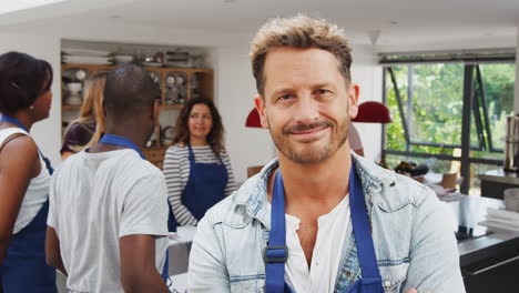 Portrait-Of-Smiling-Mature-Man-Wearing-Apron-Taking-Part-In-Cookery-Class-In-Kitchen