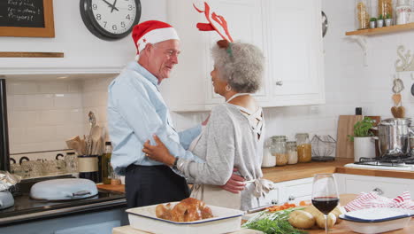 Una-Pareja-De-Ancianos-Amorosos-Vestidos-Con-Disfraces-Y-Astas-Bailan-En-La-Cocina-Mientras-Preparan-La-Cena-De-Navidad