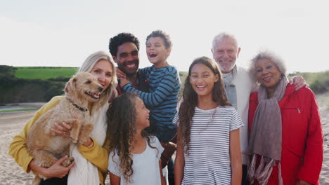 Portrait-Of-Active-Multi-Generation-Family-With-Pet-Dog-On-Winter-Beach-Vacation