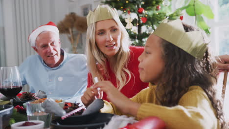 Mutter-Mit-Tochter-Und-Großvater-Am-Tisch-Lesen-Weihnachtscracker-Witze-Während-Des-Essens-Zu-Hause