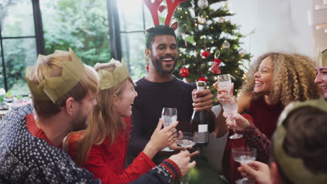 Gruppe-Von-Freunden,-Die-Mit-Champagner-Feiern,-Nachdem-Sie-Das-Weihnachtsessen-Zu-Hause-Genossen-Haben