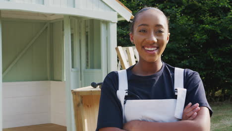 Male-Carpenter-With-Female-Apprentice-Building-Outdoor-Summerhouse-In-Garden